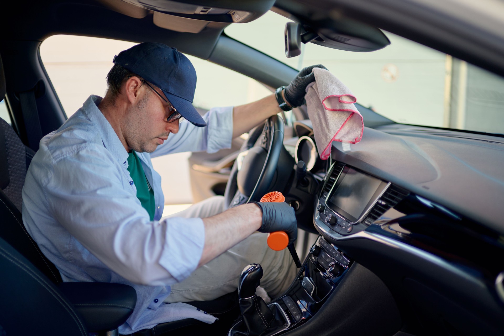 Car detailer cleaning vehicle interior with brush and cloth